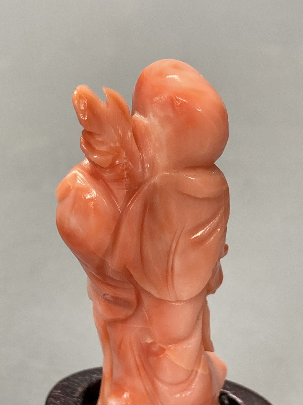A Chinese carved coral figure of Shou Lao, on inlaid wooden stand, overall 81mm.